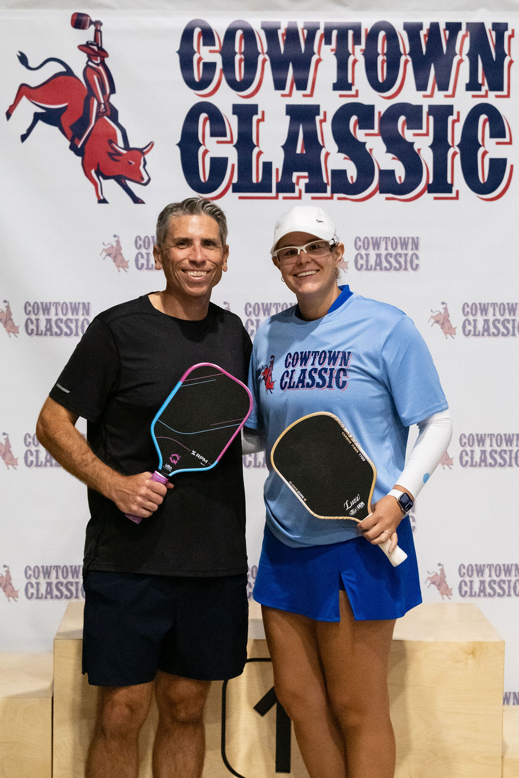A Pro-Am pair with their paddles in front of the Cowtown Classic banner
