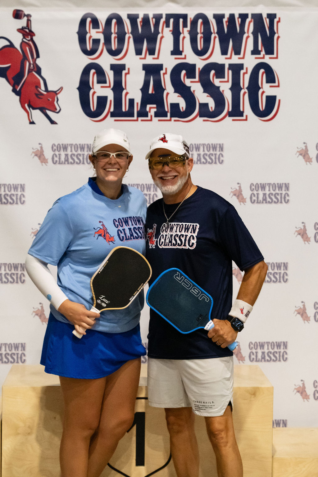A Pro-Am team with their paddles in front of the Cowtown Classic banner